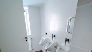 A public restroom with three urinals, a radiator, and a window. - Room in Guest Room - Single Room With Shared Bathroom and Kitchen (Forbach)