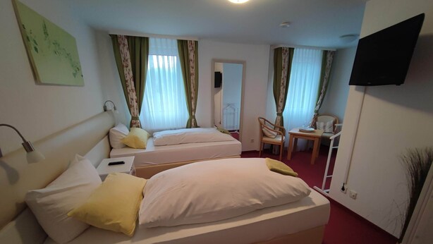 A hotel room with two beds, a desk, a chair, and a TV on the wall. - Room in Guest Room - Pension Forelle - Doppelzimmer (Forbach)