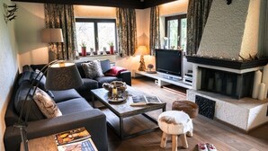 Un salon chaleureux avec une cheminée, un canapé, une table basse et un téléviseur.