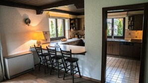 Une cuisine compacte dotée d’un îlot central, de tabourets de bar, d’une fenêtre offrant une belle vue et de meubles de rangement en bois.