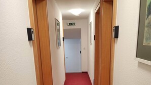 A hallway with red carpet, wooden doors, and framed pictures on the walls. - Room in Guest Room - Single Room With Shared Bathroom and Kitchen (Forbach)