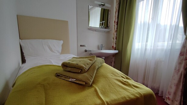 A hotel room with a bed, a bathroom, and a window with curtains. - Room in Guest Room - Single Room With Shared Bathroom and Kitchen (Forbach)