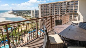 Ein Balkon mit Blick auf einen Strand, einen Poolbereich und ein Hochhaus.