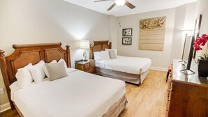 A bedroom with two beds, wooden headboards, a ceiling fan, bedside lamps, a wooden dresser, and a mirror. - Coastal Retreat 3 Bedroom Oceanfront 4th Floor (North Myrtle Beach)
