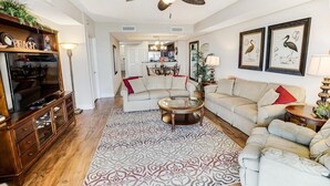 A living room with a sofa, a coffee table, a TV, and a ceiling fan. - Coastal Retreat 3 Bedroom Oceanfront 4th Floor (North Myrtle Beach)