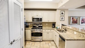 A modern kitchen with white cabinets, a stainless steel stove, a microwave, and a dishwasher. - Relax in Style 3 Bdrm Condo with King and Queen (North Myrtle Beach)
