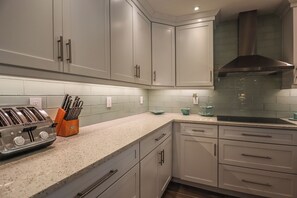 Una cocina moderna con armarios grises, una campana extractora de acero inoxidable y una encimera de granito.