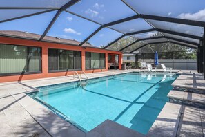 Ein Swimmingpool mit überdachtem Bereich, klarem, blauem Wasser und einem roten Gebäude mit großen Fenstern.