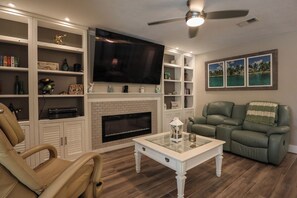 A living room with a fireplace, a television, a leather sofa, and a coffee table.