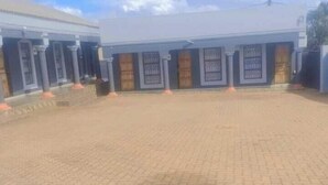 A building with a paved courtyard, columns, and a gated entrance. - Zwizwo Guest House (Thohoyandou)