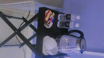 Una mesa con una botella de agua, un vaso y una taza.