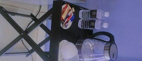 A table with a water bottle, a coffee maker, and a cup.