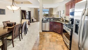 A modern kitchen with dark wood cabinets, stainless steel appliances, and a stone tile floor. - 2nd Flr Oasis: Oceanfront Bliss with King Bed (North Myrtle Beach)