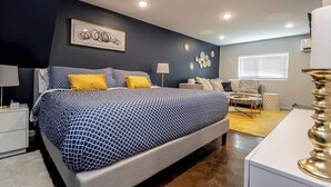 A modern bedroom with a bed, bedside tables, a sofa, and decorative wall art. - Walk to Oaklawn Casino! Luxe Studio w/King Bed (Hot Springs)