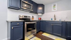 A kitchen with dark blue cabinets, stainless steel appliances, a microwave, oven, and a red coffee maker. - Walk to Oaklawn Casino! Luxe Studio w/King Bed (Hot Springs)