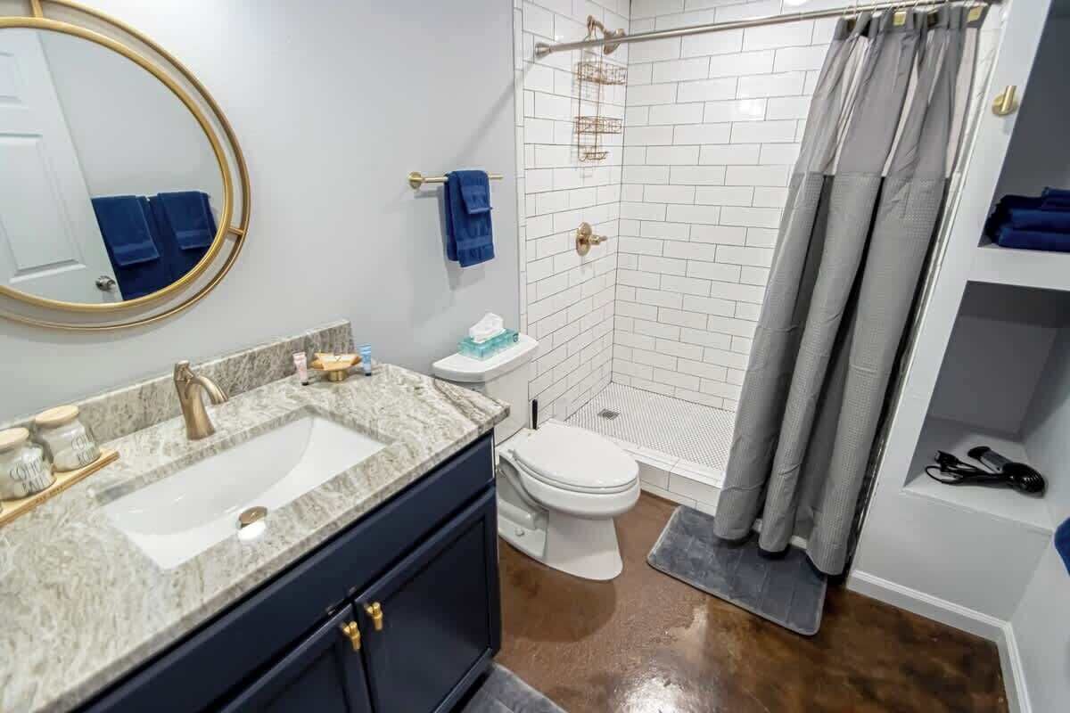 A bathroom with a sink, toilet, shower, and a mirror.