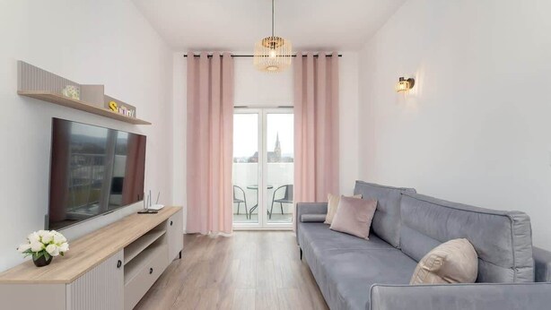 Ein modernes Wohnzimmer mit einem Flachbildfernseher, einem grauen Sofa und einer Holz-Unterhaltungsecke.