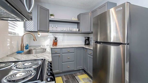 A modern kitchen with grey cabinets, a stainless steel refrigerator, a stove, and a coffee maker. - Luxury Studio, 3-Min Walk to Oaklawn Casino (Hot Springs)