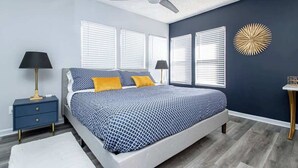 A bedroom with a bed, two bedside tables, a ceiling fan, and a decorative wall piece. - Luxury Studio, 3-Min Walk to Oaklawn Casino (Hot Springs)