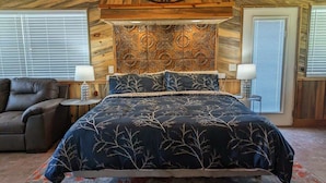 A bedroom with a large bed, a chair, and a decorative wall panel. - Lakeside Chalet w/Game Room & Private Boat Slip (Garland County)