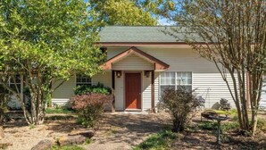 A single-story house with a front porch, a door, and a small garden with rocks and plants. - Lakeside Chalet w/Game Room & Private Boat Slip (Garland County)