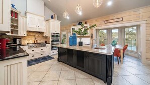 Una cocina con armarios blancos, una isla grande e iluminación colgante.