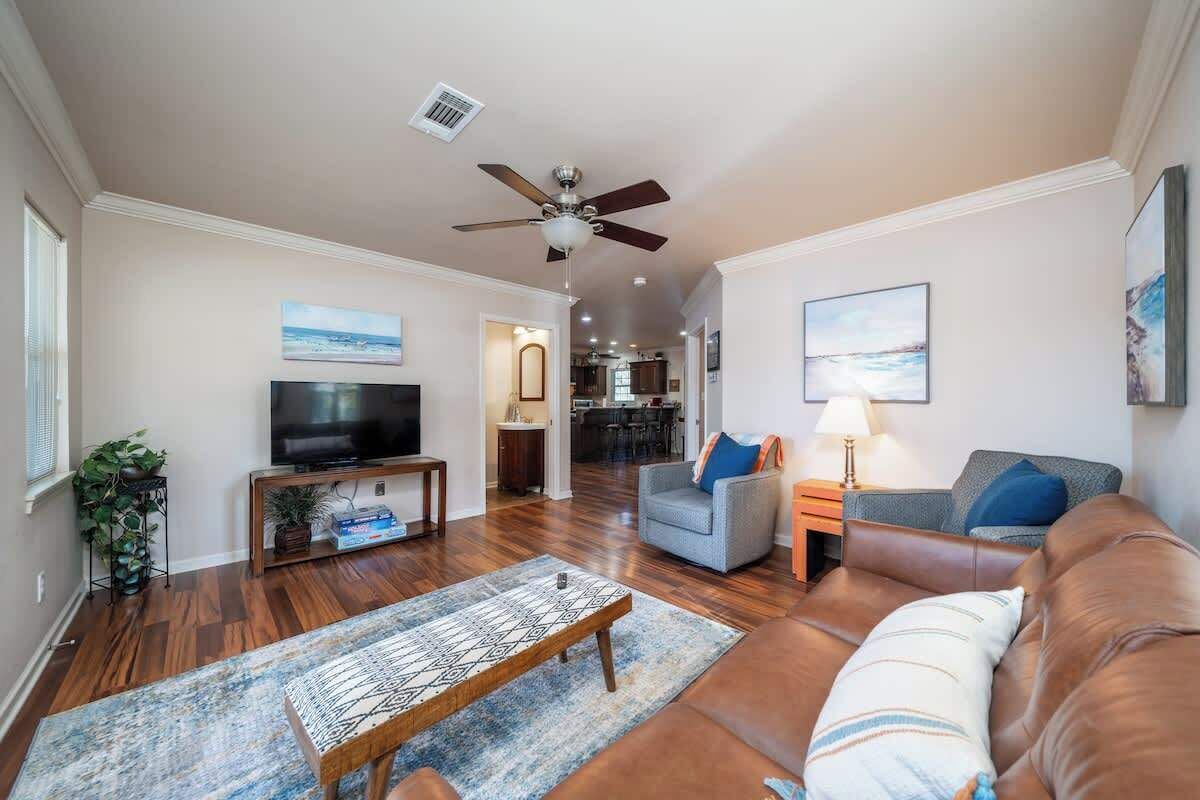 Ein Wohnzimmer mit Fernseher, Deckenventilator, Sofa, Couchtisch und Teppich.