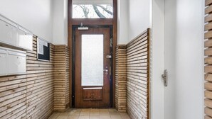 Un estrecho pasillo con paneles de madera en las paredes, piso de baldosas y una puerta al final.