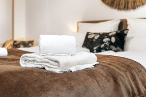 Une serviette blanche, soigneusement pliée, est posée sur un couvre-lit marron dans une chambre d’hôtel.