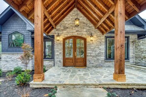 A stone exterior with a wooden porch and a large double door. - COVE VALLEY SPLASH! WOW!!! (Sevierville)