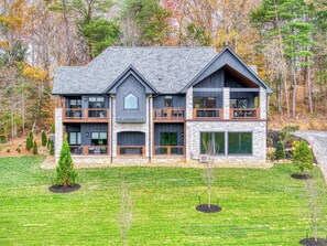 A modern two-story house with a stone facade, large windows, and a balcony. - COVE VALLEY SPLASH! WOW!!! (Sevierville)