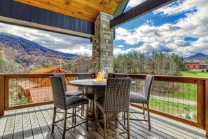 A deck with a stone pillar, a round table with chairs, and a fire feature. - COVE VALLEY SPLASH! WOW!!! (Sevierville)