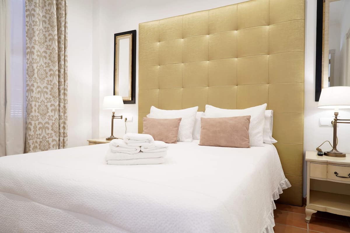 A hotel room with a large bed, a headboard, a nightstand, and a mirror.