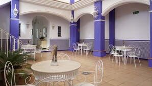 A spacious indoor area with multiple round tables and chairs, a staircase, and decorative lighting. - Palacete Real (Almonte)