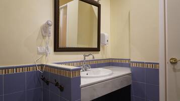 A bathroom with a sink, mirror, hairdryer, and towel rack.
