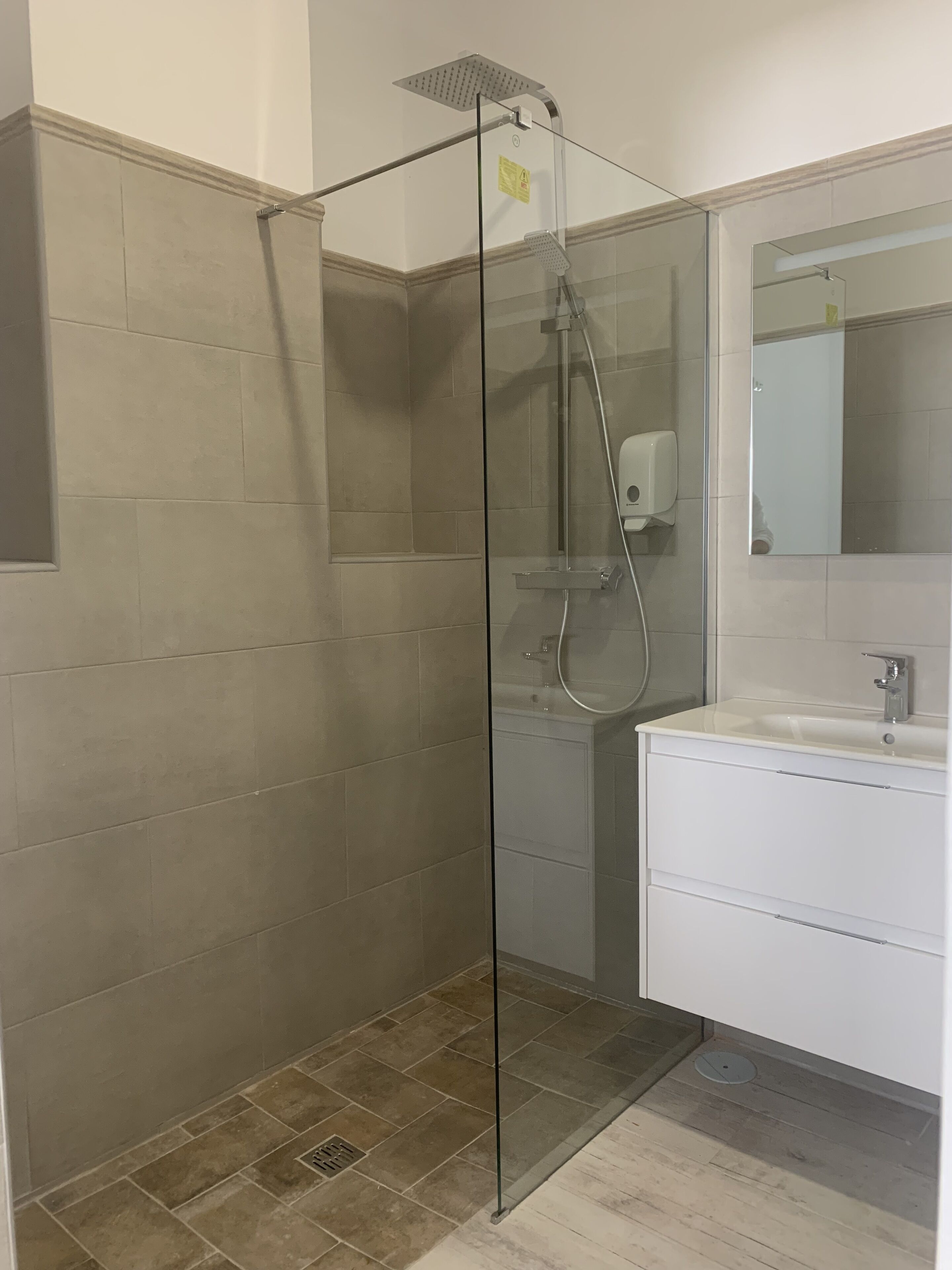 A modern bathroom with a glass-enclosed shower, a white sink, and a mirror above it.