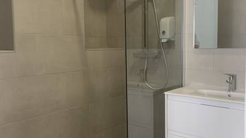 A modern bathroom with a glass-enclosed shower, a white sink, and a mirror above it.
