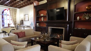 A living room with a fireplace, a television, and a dining area with a table and chairs. - Palacete Real (Almonte)