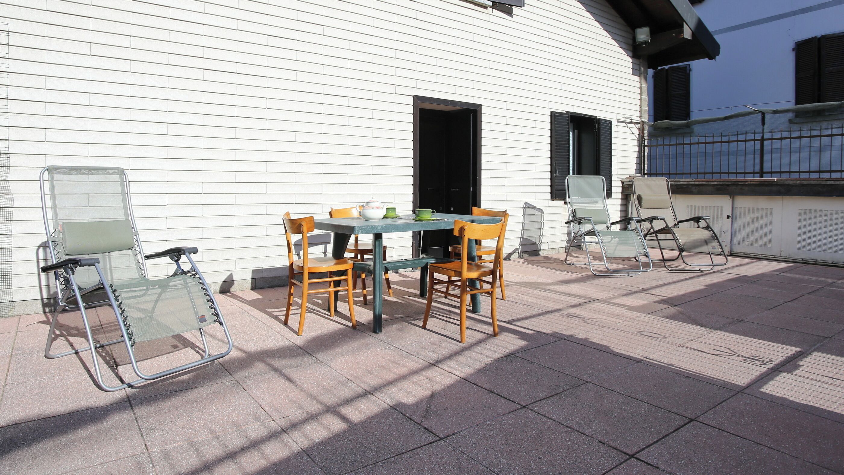 Un patio al aire libre con una mesa, sillas, una puerta y una ventana.