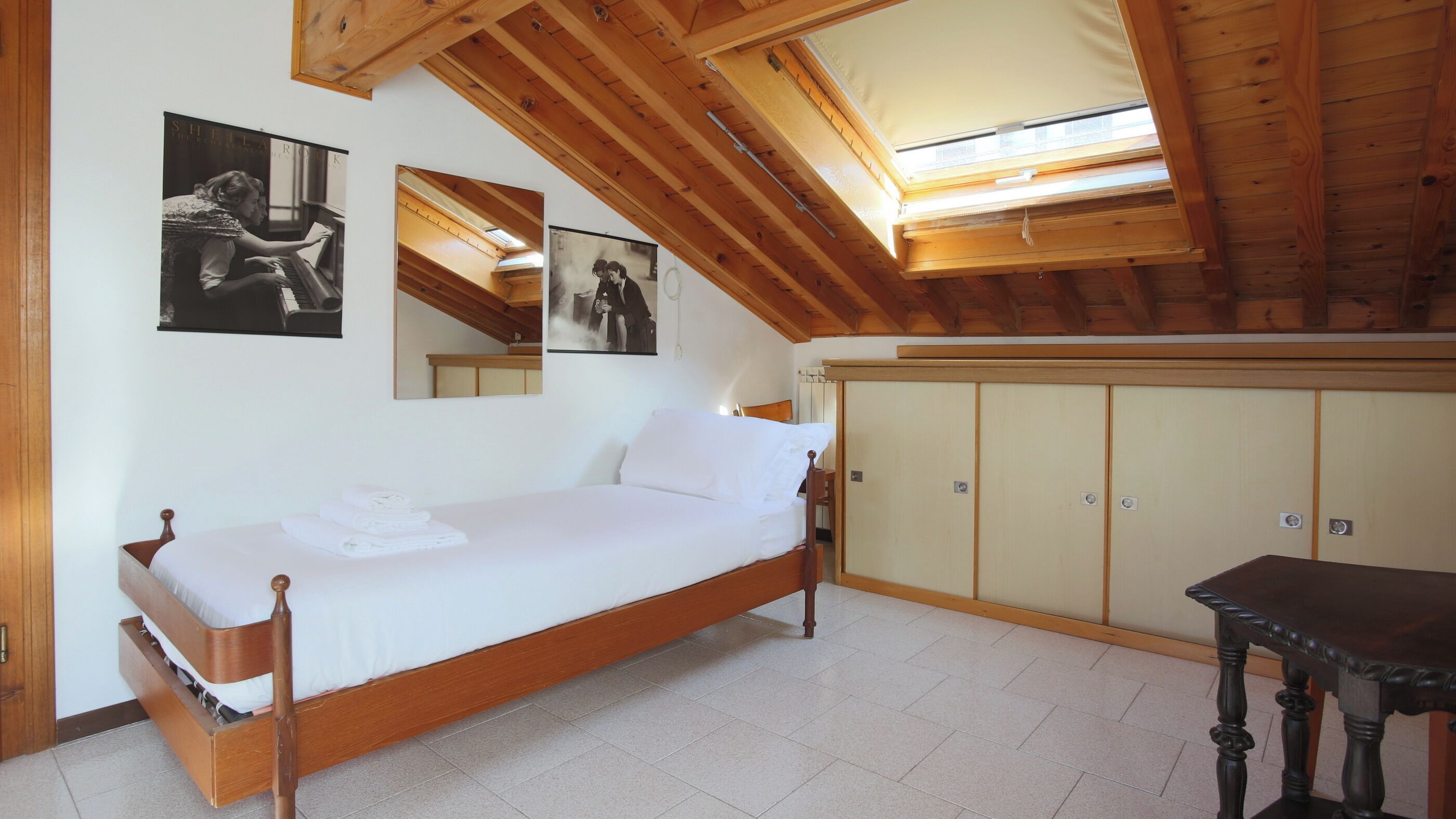 Un dormitorio con una cama de madera, un armario y una mesita.