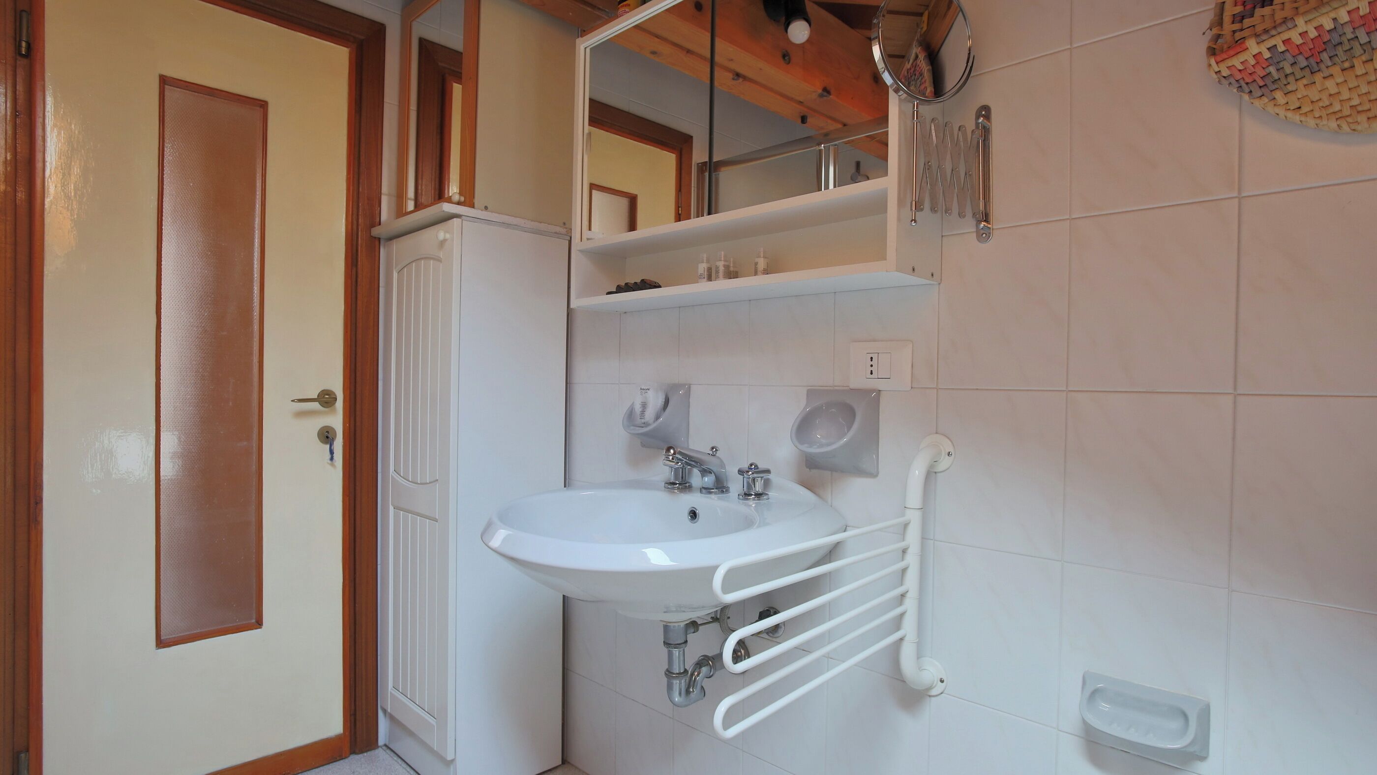 A bathroom with a white sink, a mirror, a towel rack, and a toilet.
