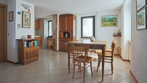 Uma cozinha ampla com armários de madeira, uma mesa de jantar com cadeiras e piso ladrilhado.