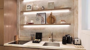 Une cuisine moderne dotée d’un plan de travail en marbre, d’étagères intégrées et de divers appareils, notamment une machine à café, un grille-pain et une bouilloire.