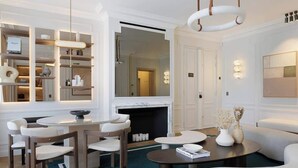 Un salon moderne avec une cheminée, un coin repas avec des meubles blancs et une bibliothèque où sont exposés des articles de marques de luxe.