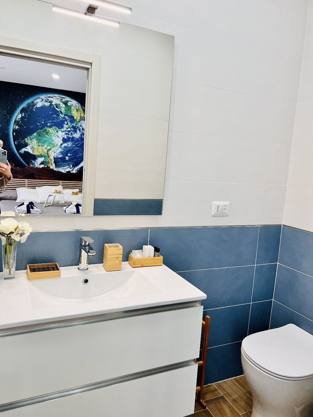 A bathroom with a large mirror, a sink, and a toilet.