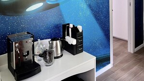 Une pièce dont un mur est décoré d’une fresque représentant un vaisseau spatial, avec une machine à café et un verre d’eau posés sur un comptoir.