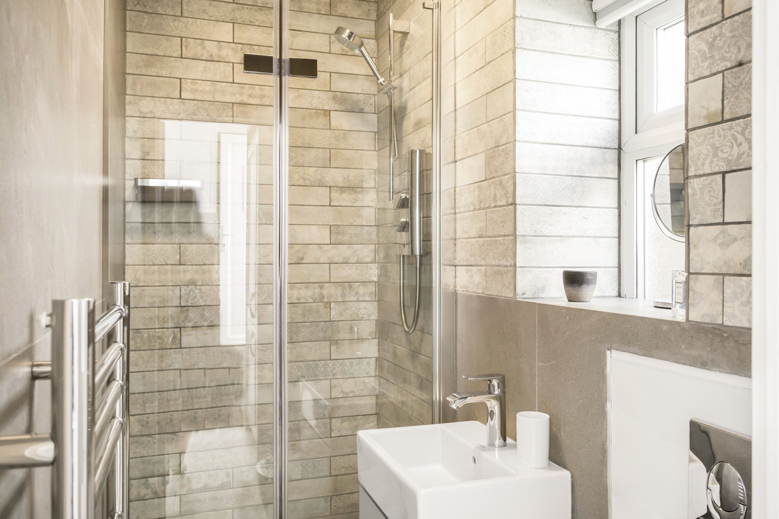 Un baño moderno con ducha de vidrio, un lavamanos blanco y un espejo grande.