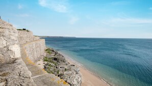 A coastal stone pathway leading to a beach with clear blue water. - Loe Cottage (Helston)