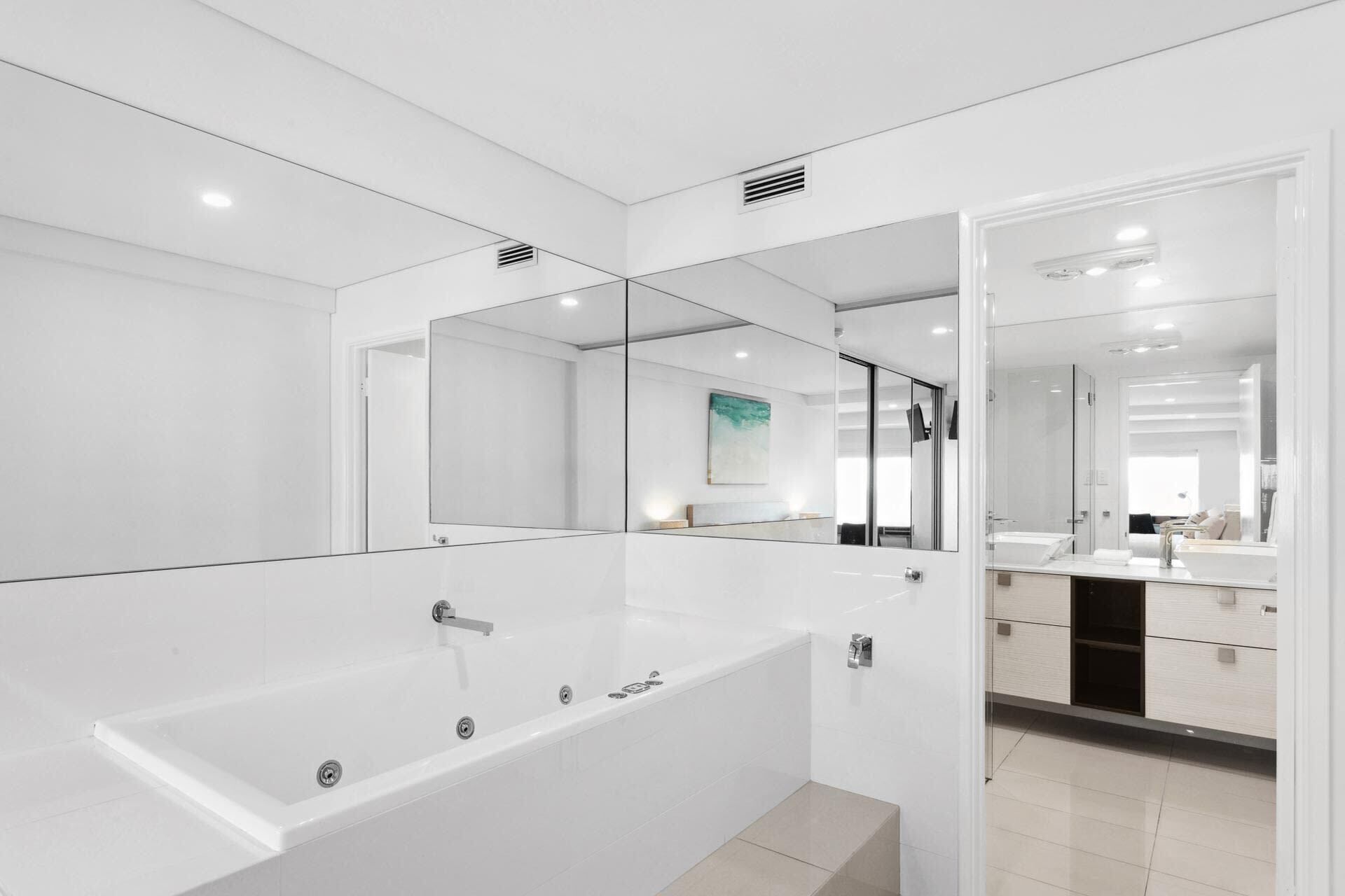 Uma casa de banho moderna com uma banheira grande, um espelho e uma pia.