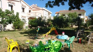A grassy outdoor area with a slide, a small table, and two chairs. - Apartments Danijela Novalja (Novalja)
